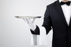 Waiter holding empty silver tray over gray background